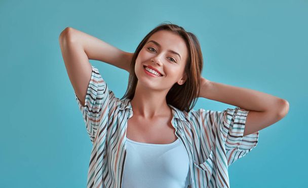 Attractive young woman isolated on blue background. Portrait of happy girl posing and smiling. - Foto, Imagem