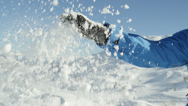 Portret slowmotion close-up: Vrolijke snowboarder verse poeder sneeuw overgeven in de lucht in zonnige mountain skiresort. Glimlachend jonge skiër spelen met verse sneeuw op mooie winterdag - Video