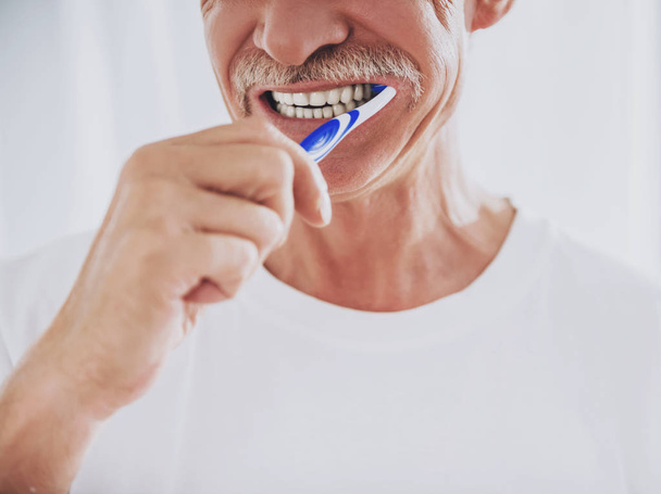 Close up. Senior Man Brushing Teeth in Bathroom. - Фото, изображение