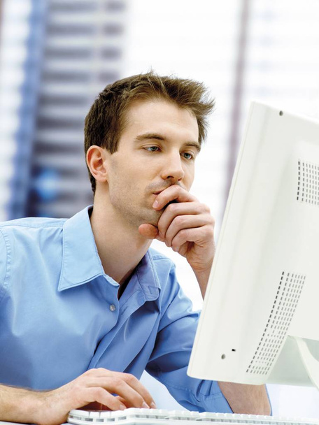 serious Businessman using a computer in office and holding hand on chin  - Foto, Bild