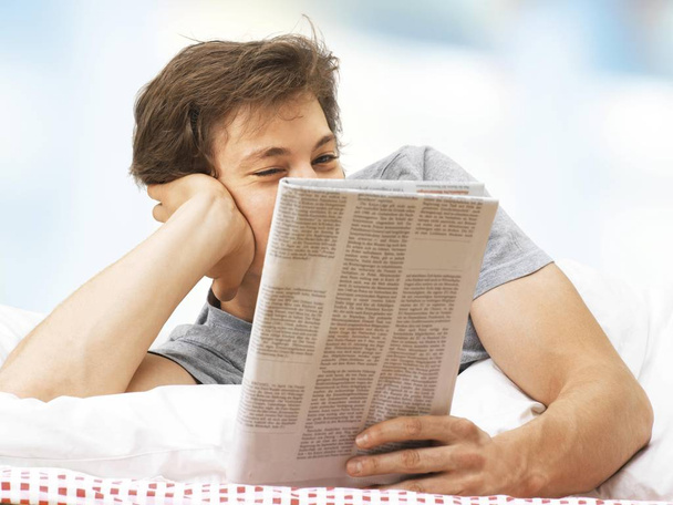 man reading newspaper and relaxing in bed  - Fotó, kép