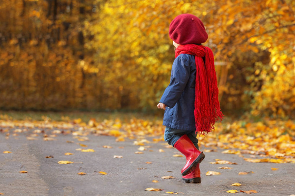 Happy autumn. Little girl laughs and runs in galoshes through the autumnal park. - Фото, изображение