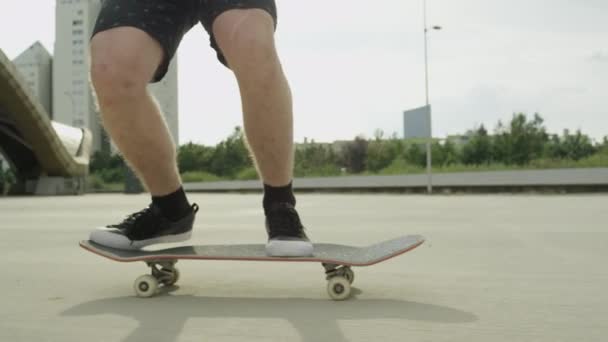 Slow Motion close-up: Onherkenbaar skateboarder skateboarden en springen flip ollie truc op beton straat. Extreme close-up van skateboarder de benen springen flip truc met skateboard in de stad - Video