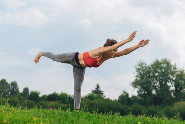 Dark-haired athletic woman doing standing yoga pose - Фото, зображення