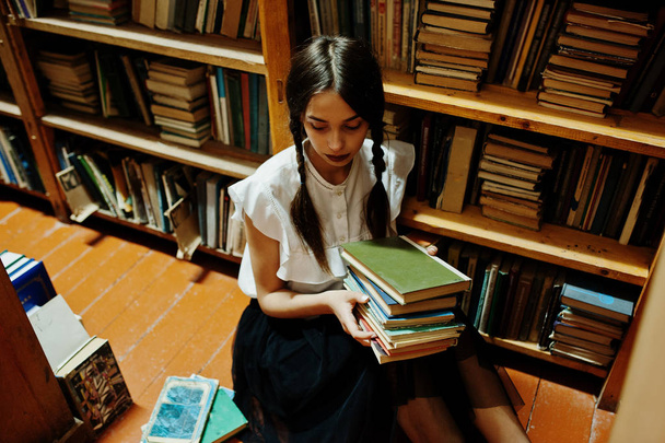 Meisje met pigtails in witte blouse op oude bibliotheek. - Foto, afbeelding