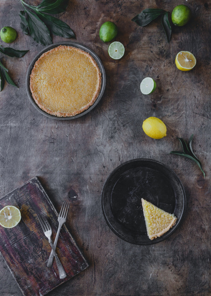 elevated view of tasty lemon pie and limes with lemons on wooden table - Foto, Imagem