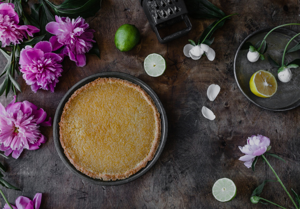 top view of tasty lemon pie and violet peonies on wooden table - Foto, immagini