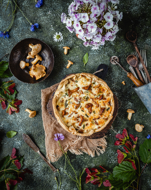 Widok góry apetyczny quiche z pieczarkami i kwiaty doniczkowe na drewnianym stole - Zdjęcie, obraz