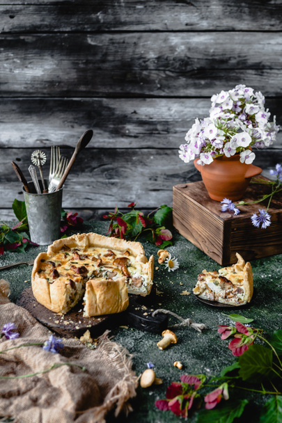 yummy pie with mushrooms and potted flowers on wooden table - Fotoğraf, Görsel