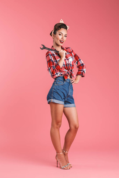 Photo of amazing young pin-up woman isolated over pink background wall holding wrench. - Φωτογραφία, εικόνα