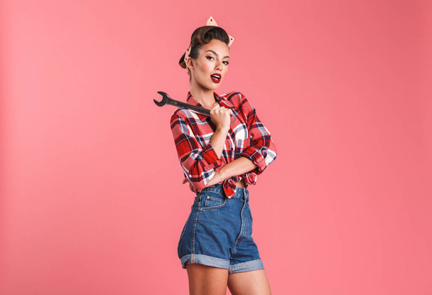 Photo of amazing young pin-up woman isolated over pink background wall holding wrench. - Foto, afbeelding
