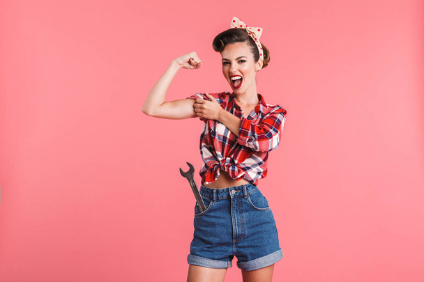 Photo of gorgeous strong young pin-up woman isolated over pink background wall showing biceps. - Fotografie, Obrázek