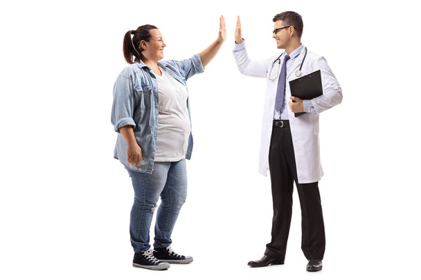 Full length profile shot of a young woman high-fiving a doctor isolated on white background - Foto, imagen