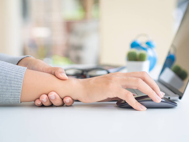 Kobieta z bliska trzymająca ból nadgarstka od używania komputera przez długi czas. Koncepcja zespołu biurowego. - Zdjęcie, obraz