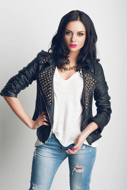 portrait of beautiful brunette model in black leather coat posing in studio - Foto, Imagem