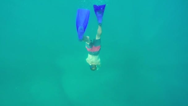 SLOW MOTION, CLOSE UP, UNDERWATER: Strong athletic man diving in stunning deep blue ocean wearing mask, snorkel and flippers, exploring sea floor and having fun on active exotic summer vacation - Footage, Video
