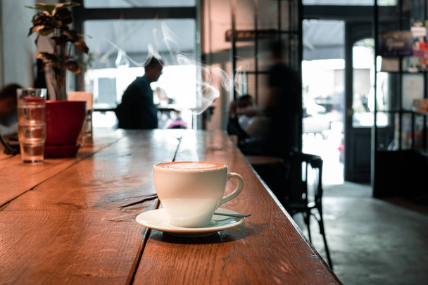 φλιτζάνι καφέ στο τραπέζι από ξύλο στο εσωτερικό του καφέ - Φωτογραφία, εικόνα