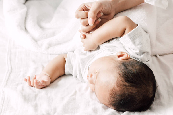 Mother holding sleeping baby hand on white bed.Love of family concept - Foto, Imagen