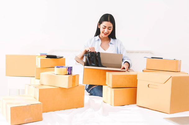Mujer joven freelancer que trabaja sme negocio de compras en línea y zapatos de embalaje con caja de cartón en la cama en casa - Negocios concepto de envío y entrega en línea
 - Foto, Imagen