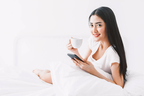 Happy woman relaxing and using smartphone on the bed at home.woman checking social apps with smartphone - Фото, зображення