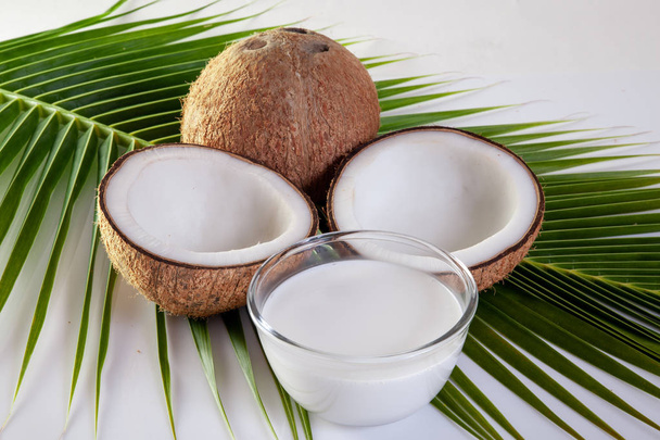 Kookospähkinä, jossa on maitoa kookoslehtien taustalla
 - Valokuva, kuva