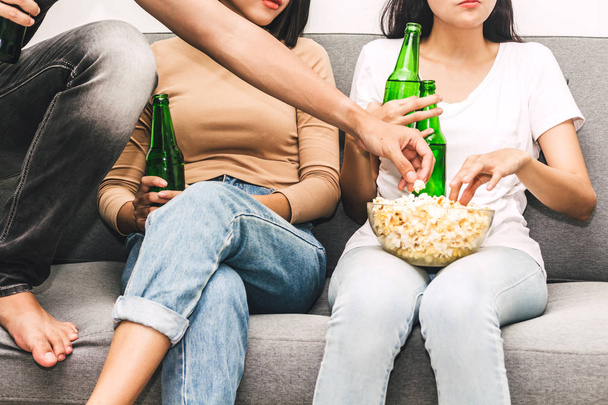 Groep vrienden eten popcorn en drinken bier samen tv kijken op de Bank thuis. Vriendschap en partij concept - Foto, afbeelding