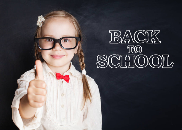 Boldog gyermek lány szemüvegét a hüvelykujjával felfelé először megy az iskolába. Vissza a concept iskolai - Fotó, kép