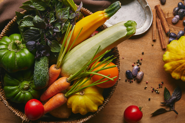 Basket filled with farm vegetables on wooden table - Foto, Bild
