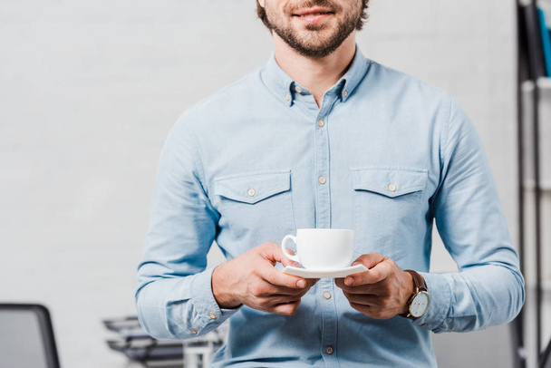 cropped shot of young businessman with cup of coffee at modern office - Valokuva, kuva