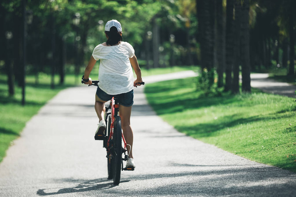 Жінка їде на гірському велосипеді в тропічному парку
 - Фото, зображення