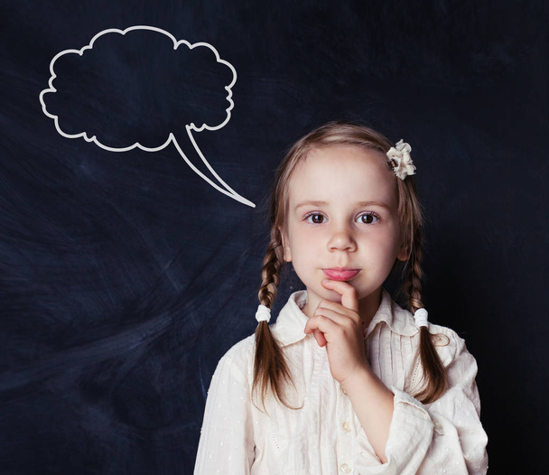Παιδί σκέψης στον μαυροπίνακα σχολείο με κιμωλία σύννεφα ομιλίας. Σχολείο κορίτσι πορτρέτο - Φωτογραφία, εικόνα