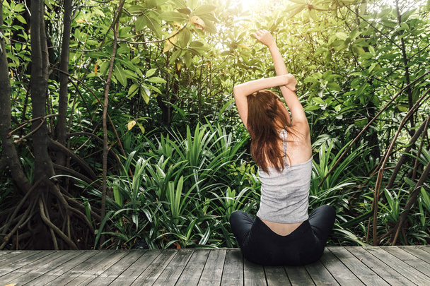 Γυναίκα τεντώστε τα χέρια της να χαλαρώσουν και να απολαύσουν με φρέσκο αέρα πράσινο της φύσης - Φωτογραφία, εικόνα