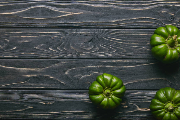 Green bell peppers on dark wooden table - 写真・画像