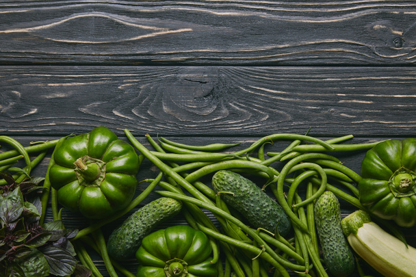 Green summer vegetables on dark wooden table - Фото, изображение