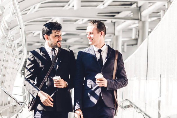 Dos hombres de negocios sonrientes hablando y caminando por la ciudad
 - Foto, imagen