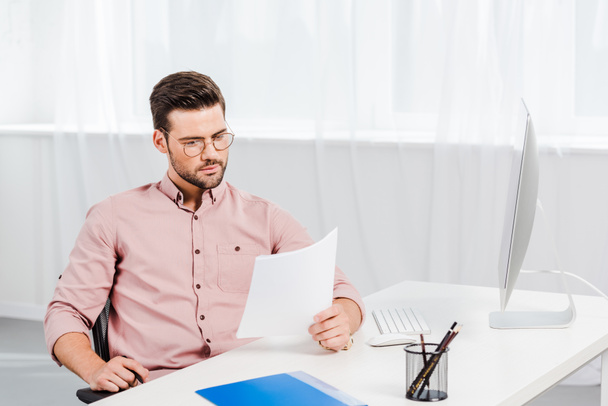 concentrated young businessman reading documents at workplace - Photo, Image