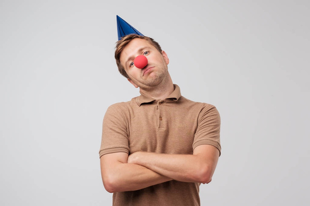 Funny mature man with red clown nose looking sadly at camera. Nobody came to his birthday party and he is offended. - Photo, Image