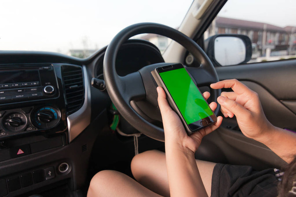 Hand of woman using smartphone with blank green screen monitor in SUV car - Valokuva, kuva