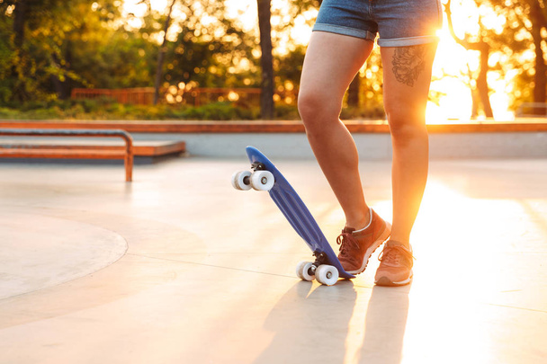 Cropped image of a young girl standing with skateboard at the park - Fotó, kép