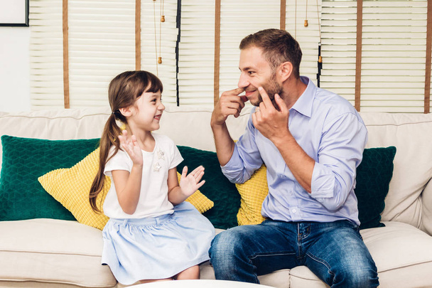 Father with little daughter having fun and playing together on the sofa at home.Love of family and father day concept - Фото, зображення