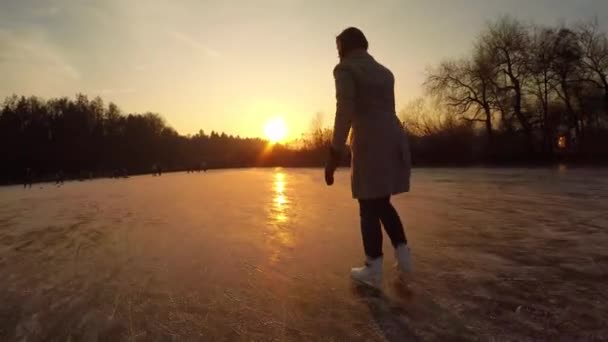 CLOSE UP: Female recreational ice skater iceskating fast in natural rink on frozen lake at magical sunset on Christmas eve. People enjoying holidays and playing hockey with kids and friends in nature - 映像、動画