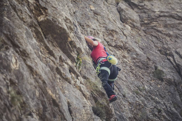 A woman mountaineer climbing a mountain rock. - Фото, изображение