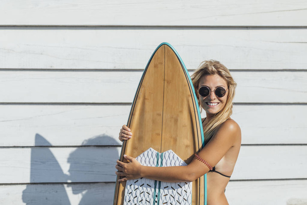 Portrait of a beautiful smiling blonde Caucasian woman surfer posing with her surf board. - Foto, Imagen