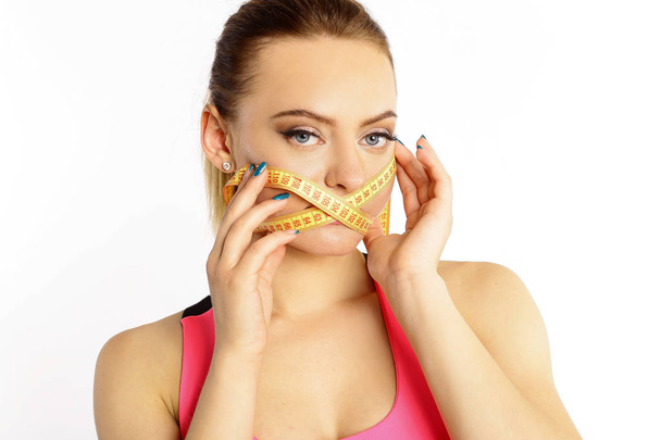 A woman with a yellow measuring tape around her mouth, a centimeter isolated on white background. Do not eat to be thin - Foto, Bild