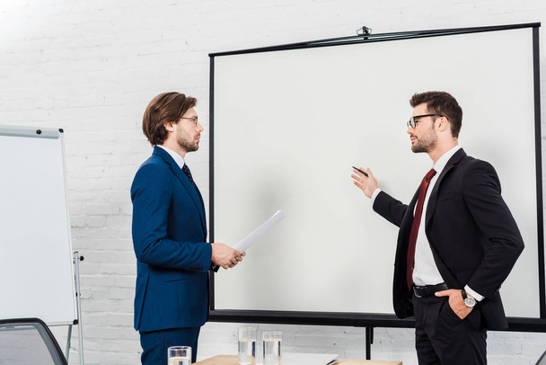 businessmen having conversation and pointing at presentation board at modern office - Photo, Image