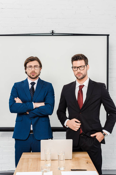 красивые успешные бизнесмены, смотрящие в камеру в современном офисе
 - Фото, изображение
