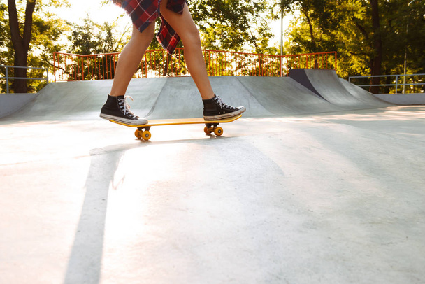 Cropped photo of young woman outdoors with skateboard. - Фото, зображення
