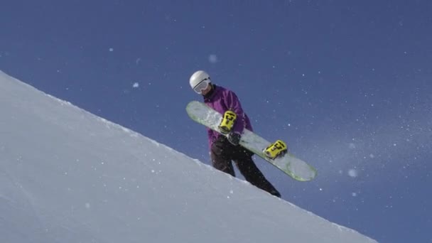 Zwolnionym tempie: Młody pro snowboarder chodzenie pod górę w snowparku halfpipe, niosąc jego pokładzie w piękny słoneczny dzień w mroźną zimę - Materiał filmowy, wideo