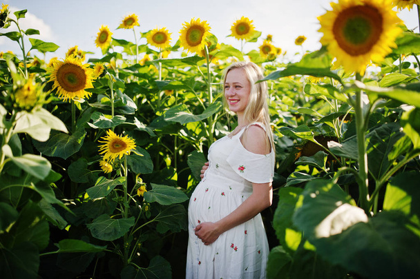 Ayçiçeği alanındaki sarışın hamile anne. Gebeliğin mutlu anları. - Fotoğraf, Görsel