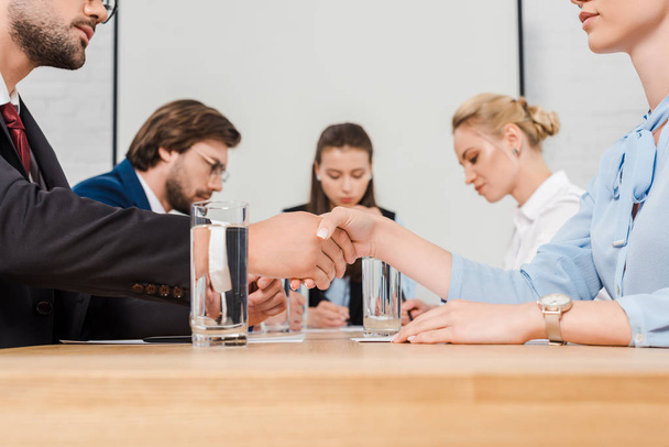 обрезанный снимок бизнес-партнеров, пожимающих руки во время конференции в современном офисе
 - Фото, изображение